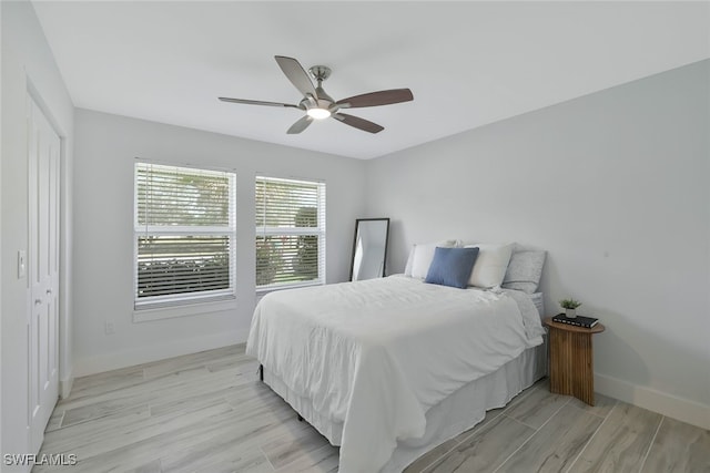 bedroom with ceiling fan, light hardwood / wood-style floors, and a closet