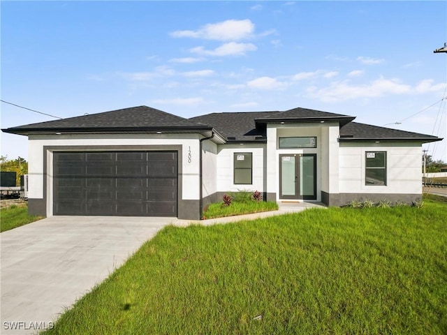 prairie-style home with stucco siding, a shingled roof, an attached garage, driveway, and a front lawn