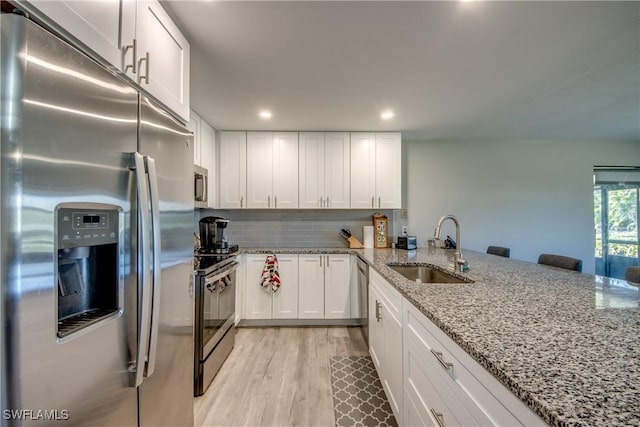 kitchen featuring white cabinets, appliances with stainless steel finishes, sink, and kitchen peninsula