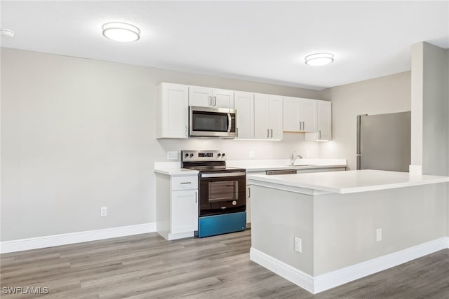 kitchen featuring stainless steel appliances, white cabinetry, sink, and light hardwood / wood-style flooring