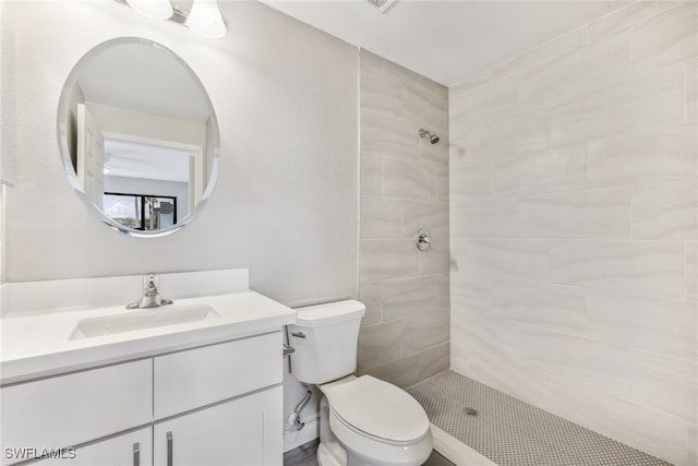 bathroom featuring a tile shower, vanity, and toilet