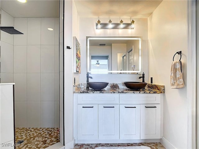 bathroom with tiled shower and vanity