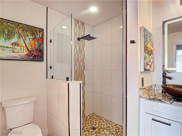 bathroom with tiled shower, vanity, and toilet