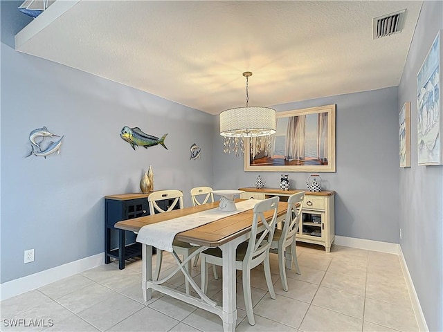 tiled dining room with an inviting chandelier and a textured ceiling