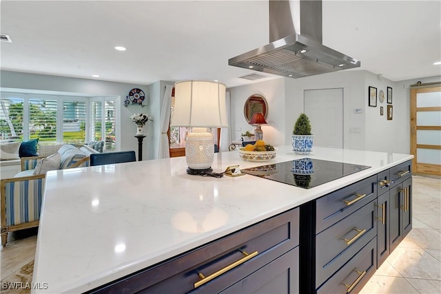 kitchen with island range hood, light stone countertops, black electric stovetop, and gray cabinetry