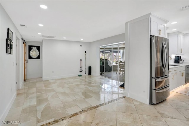 interior space with appliances with stainless steel finishes, light tile patterned floors, and white cabinetry