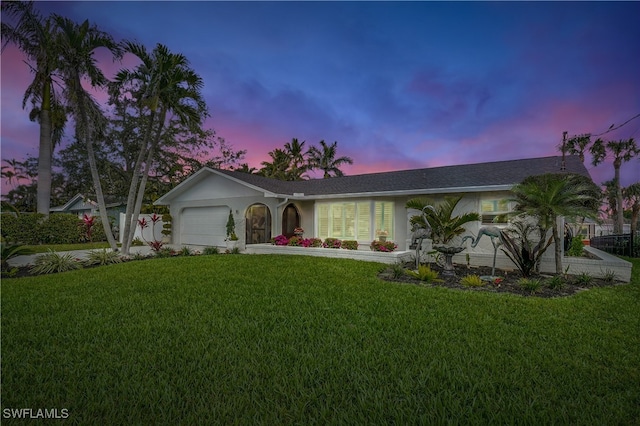 single story home featuring a garage and a yard