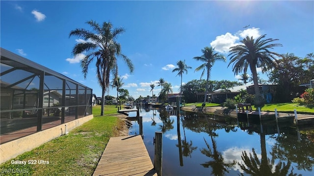 dock area with a yard, a water view, and glass enclosure