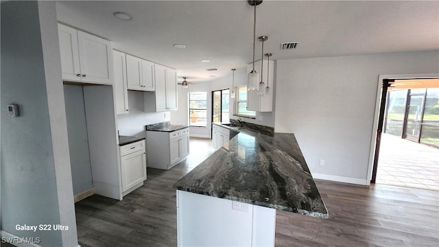 kitchen featuring sink, hanging light fixtures, dark hardwood / wood-style floors, white cabinets, and dark stone counters