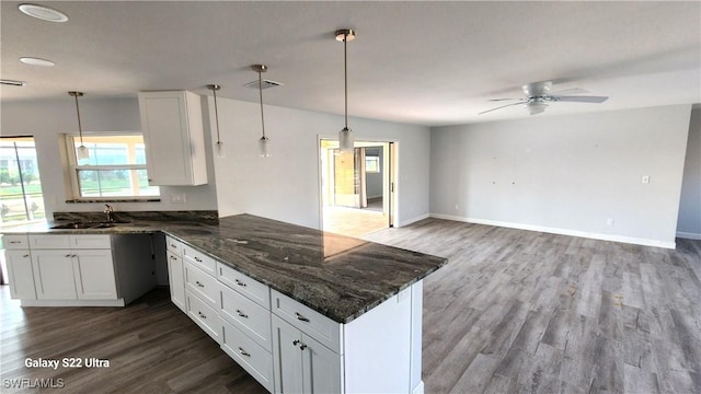 kitchen featuring white cabinetry, decorative light fixtures, kitchen peninsula, and sink