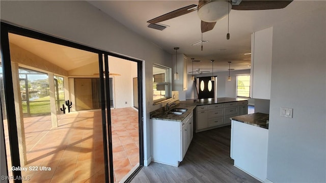 kitchen featuring white cabinetry, sink, hanging light fixtures, kitchen peninsula, and dark wood-type flooring