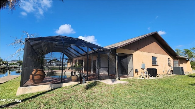 rear view of house with a water view, a yard, central AC, and glass enclosure