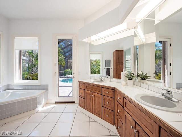 bathroom with tile patterned floors, vanity, and tiled tub