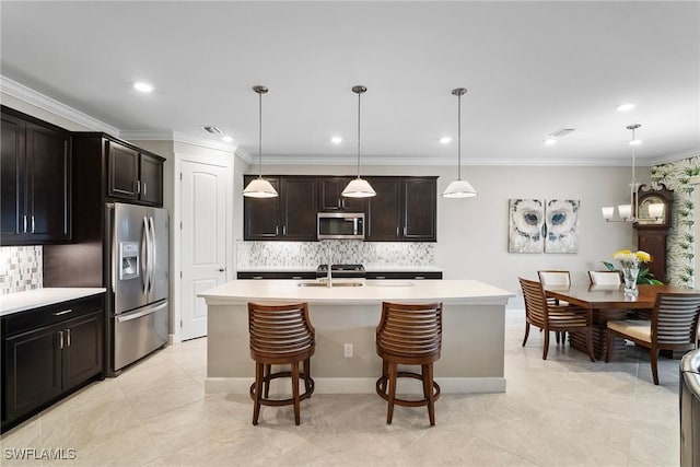 kitchen with a center island with sink, hanging light fixtures, sink, appliances with stainless steel finishes, and a kitchen breakfast bar