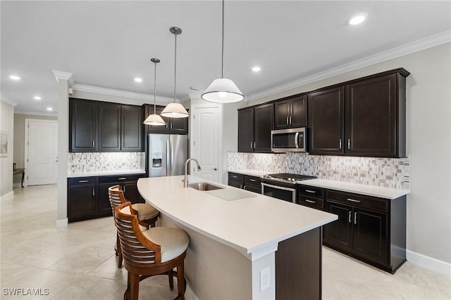 kitchen with a center island with sink, stainless steel appliances, decorative light fixtures, sink, and dark brown cabinets