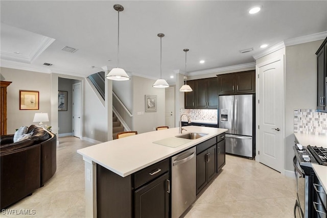 kitchen featuring appliances with stainless steel finishes, a center island with sink, decorative light fixtures, crown molding, and sink