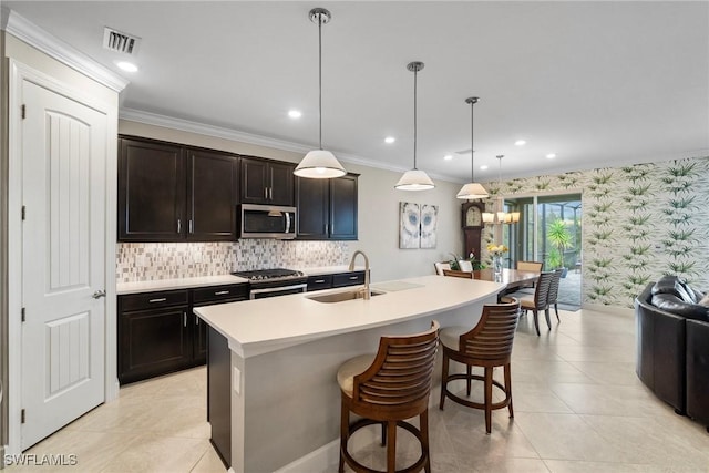 kitchen with a kitchen breakfast bar, stainless steel appliances, decorative light fixtures, sink, and a kitchen island with sink