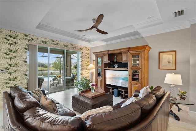 living room featuring ceiling fan, a tray ceiling, and crown molding