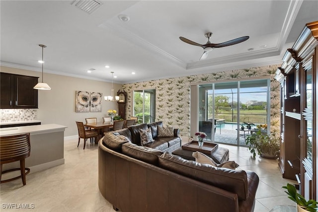 tiled living room with a tray ceiling, ceiling fan, and ornamental molding