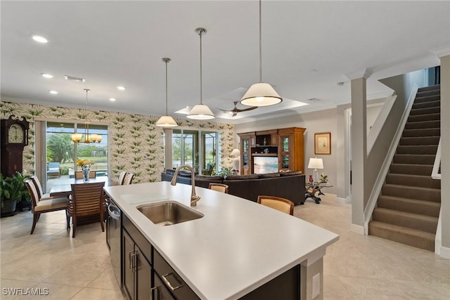 kitchen with sink, crown molding, stainless steel dishwasher, hanging light fixtures, and a kitchen island with sink