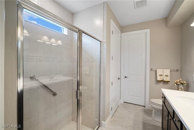 bathroom with toilet, vanity, and a shower with shower door