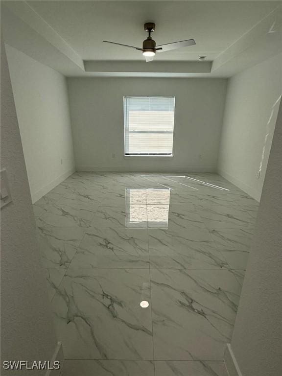 spare room featuring ceiling fan and a raised ceiling