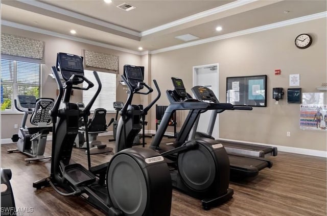 exercise room with ornamental molding, hardwood / wood-style floors, and a tray ceiling