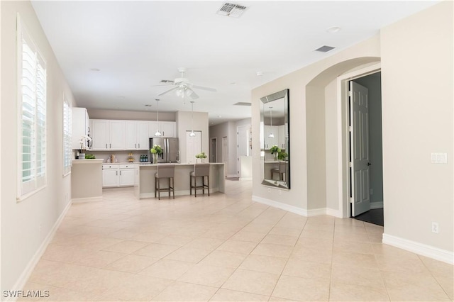 kitchen featuring a kitchen island, white cabinetry, a breakfast bar area, stainless steel refrigerator with ice dispenser, and plenty of natural light