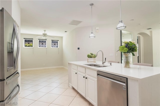 kitchen with sink, hanging light fixtures, stainless steel appliances, an island with sink, and white cabinets