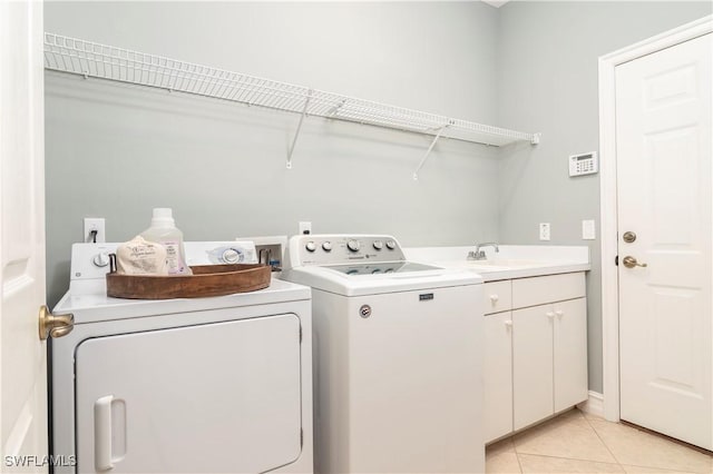 laundry area featuring cabinets, light tile patterned flooring, sink, and washer and clothes dryer