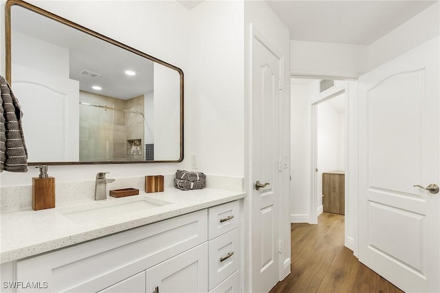 bathroom with wood-type flooring, an enclosed shower, and vanity