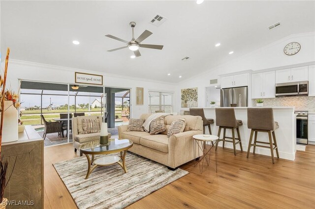 living room featuring crown molding, ceiling fan, vaulted ceiling, and light hardwood / wood-style flooring