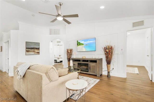 living room with hardwood / wood-style flooring, ornamental molding, and ceiling fan