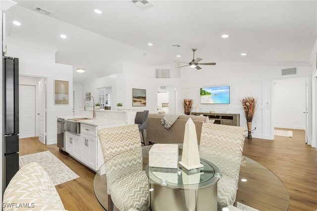 dining room with sink, crown molding, light hardwood / wood-style flooring, ceiling fan, and high vaulted ceiling