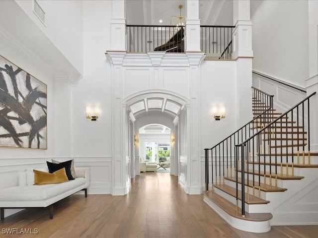 foyer entrance featuring hardwood / wood-style flooring, a high ceiling, and decorative columns