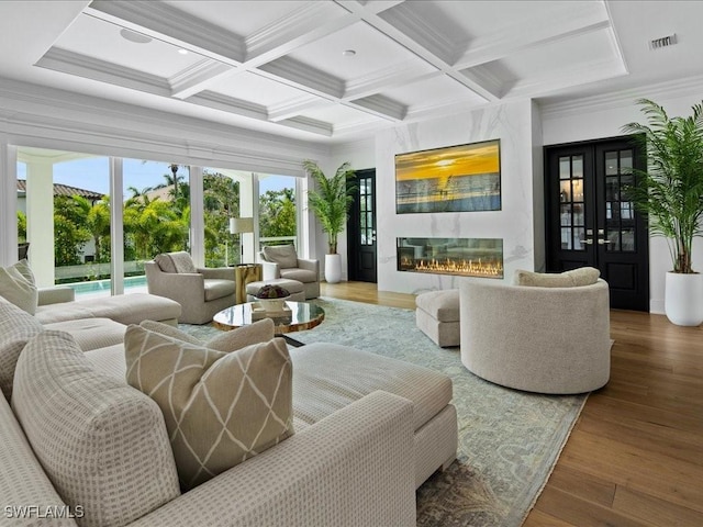 living room featuring coffered ceiling, hardwood / wood-style flooring, a fireplace, and beamed ceiling