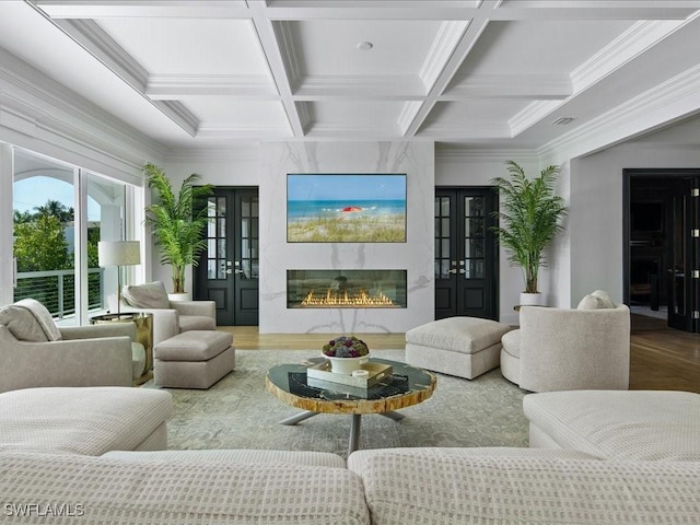 living room featuring hardwood / wood-style floors, coffered ceiling, a fireplace, ornamental molding, and french doors