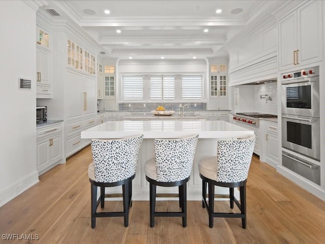 kitchen featuring white cabinetry, stainless steel appliances, a breakfast bar, and an island with sink