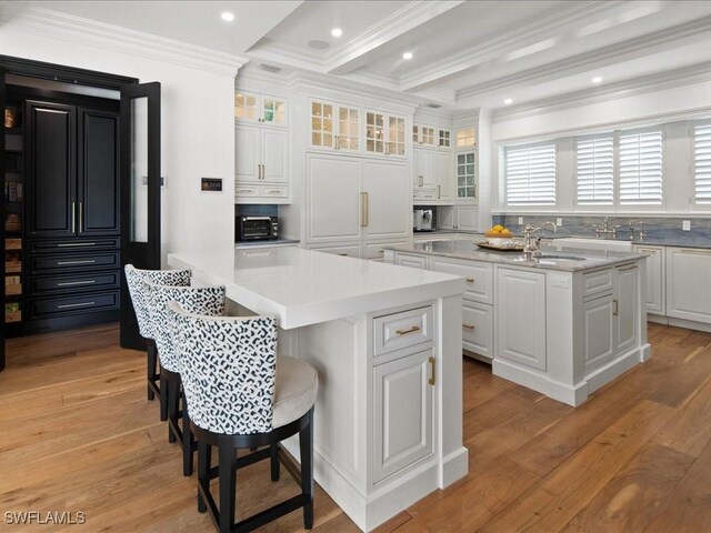 kitchen featuring white cabinetry, light hardwood / wood-style floors, and an island with sink