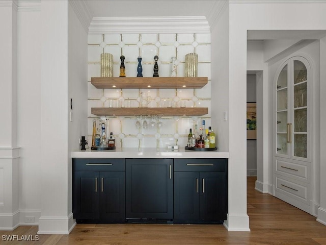 bar with crown molding, decorative backsplash, and light hardwood / wood-style flooring