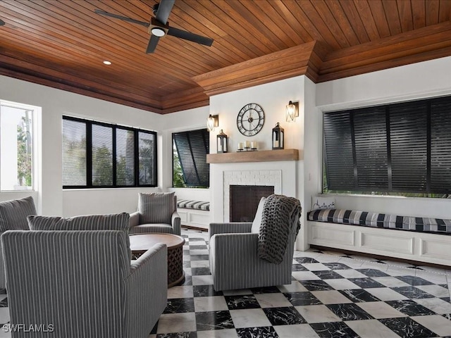 living room with wood ceiling, a fireplace, ornamental molding, and ceiling fan