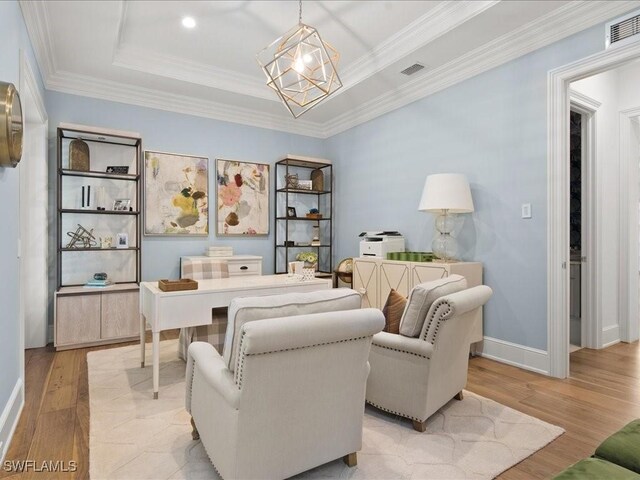 sitting room with crown molding, a tray ceiling, light hardwood / wood-style flooring, and a notable chandelier