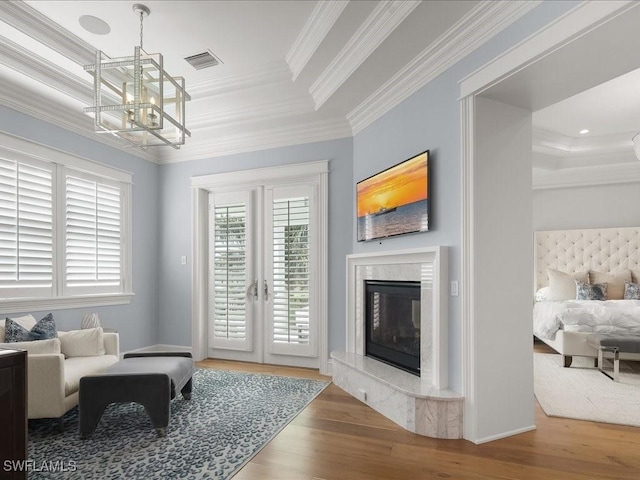 living room with hardwood / wood-style floors, a tray ceiling, a high end fireplace, and ornamental molding