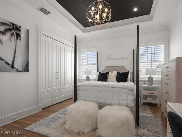 bedroom featuring ornamental molding, dark hardwood / wood-style floors, a notable chandelier, and a tray ceiling