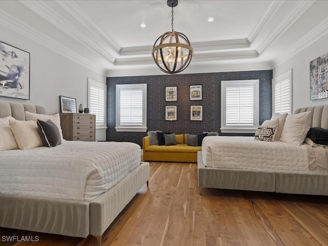 bedroom featuring ornamental molding, a tray ceiling, a chandelier, and light wood-type flooring