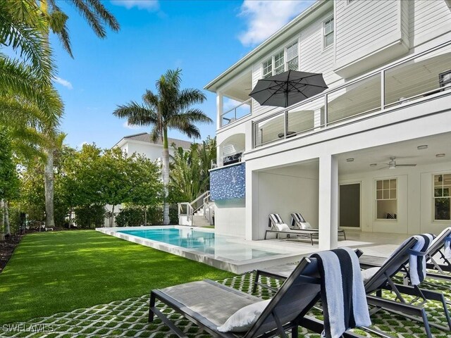 exterior space featuring a patio, a balcony, ceiling fan, and a lawn