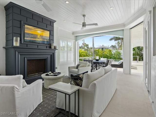 tiled living room featuring ornamental molding, ceiling fan, wooden ceiling, and a fireplace