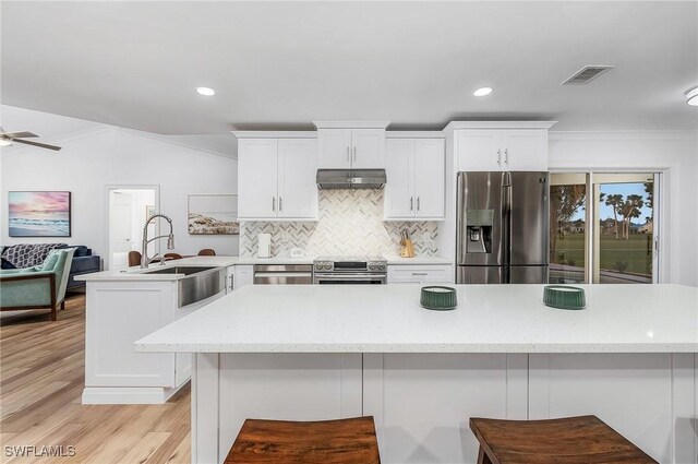 kitchen with extractor fan, appliances with stainless steel finishes, sink, and white cabinets