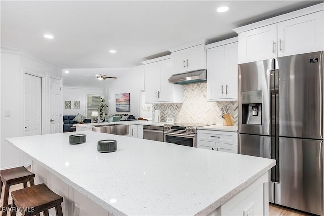 kitchen featuring white cabinetry, sink, stainless steel appliances, and a kitchen breakfast bar