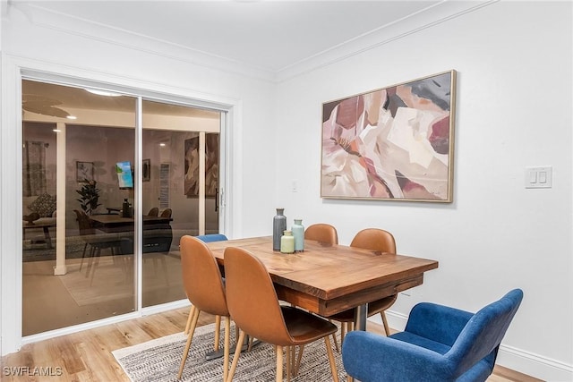 dining room with crown molding and light hardwood / wood-style flooring